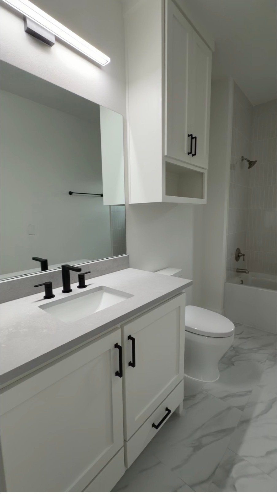 Bright remodeled bathroom with white vanity and black fixtures